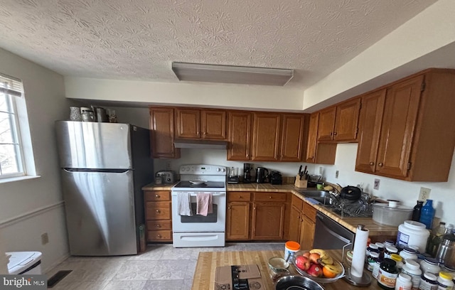 kitchen featuring sink, black dishwasher, a textured ceiling, electric range, and stainless steel refrigerator