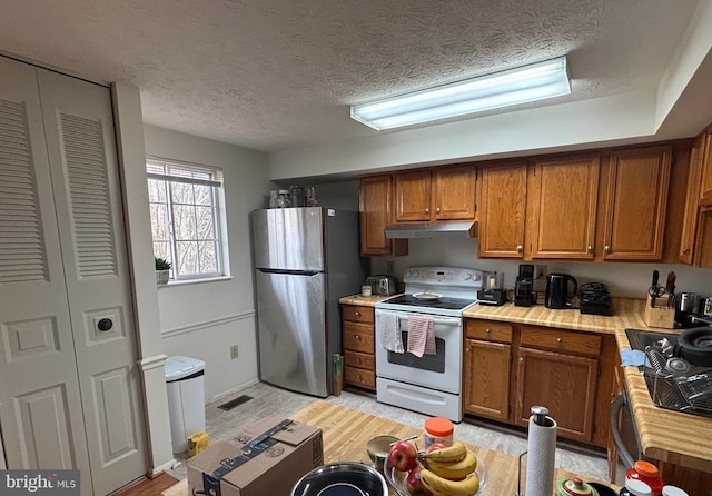 kitchen with electric stove, stainless steel fridge, and a textured ceiling