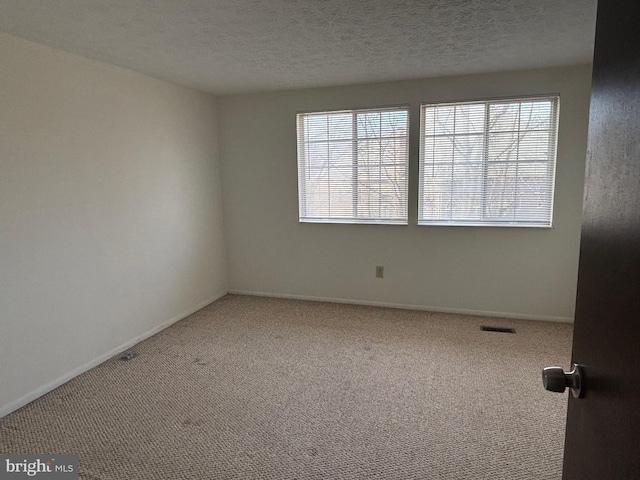 carpeted spare room featuring a textured ceiling