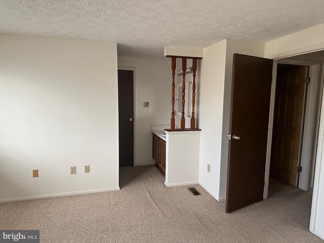 spare room featuring a textured ceiling and light colored carpet