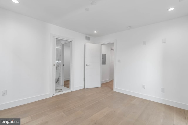 empty room with electric panel and light wood-type flooring