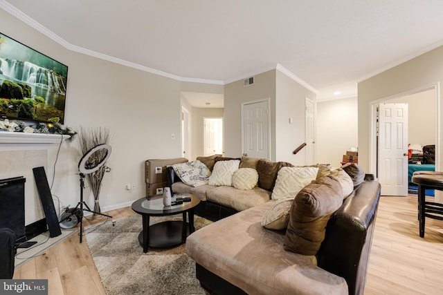 living room with ornamental molding, a fireplace, and light hardwood / wood-style floors