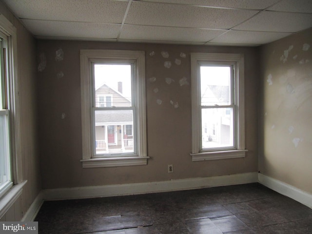 empty room with a paneled ceiling and a wealth of natural light