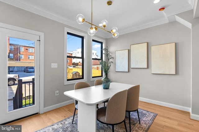 dining area with an inviting chandelier, ornamental molding, and light wood-type flooring