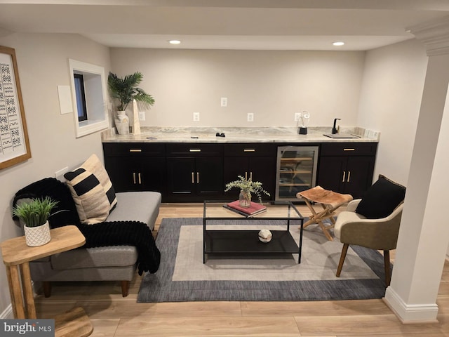 interior space featuring sink, light hardwood / wood-style flooring, light stone countertops, beverage cooler, and ornate columns