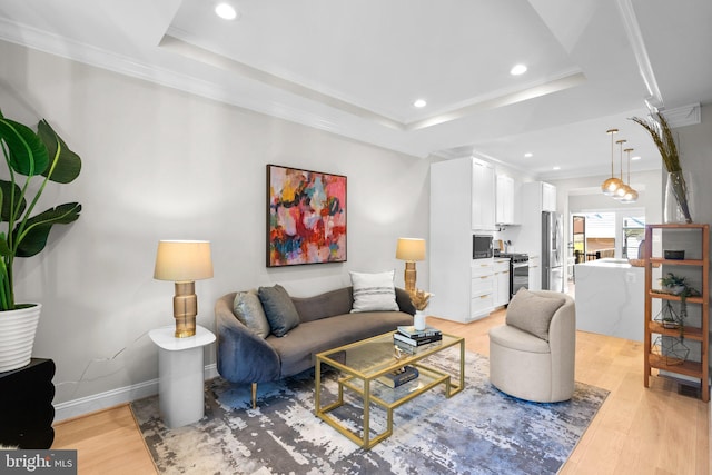 living room with ornamental molding, light hardwood / wood-style floors, and a tray ceiling