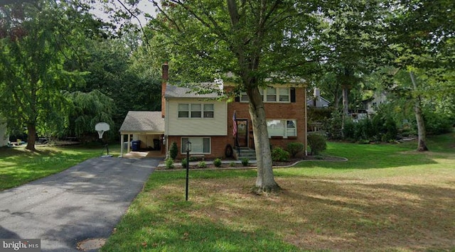 view of front of property featuring driveway, a front lawn, a carport, and brick siding