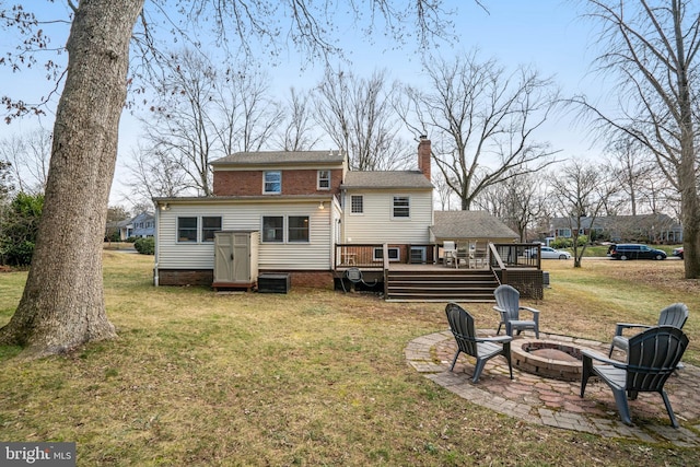 back of house with an outdoor fire pit, a chimney, a lawn, and a wooden deck