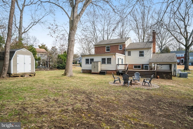 back of house featuring a storage shed, an outdoor fire pit, a chimney, a wooden deck, and an outdoor structure