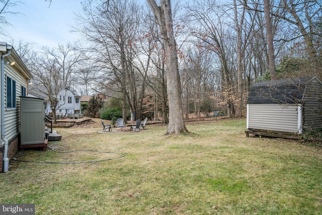 view of yard with an outbuilding, a fire pit, and a shed