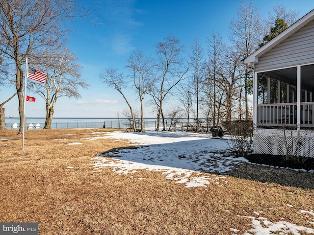 view of yard featuring a sunroom and a water view