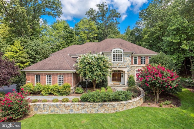 view of front of property featuring stone siding, a front lawn, and brick siding