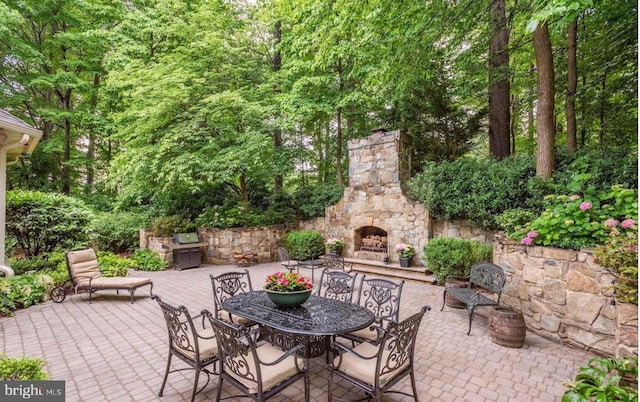 view of patio / terrace with outdoor dining space and an outdoor stone fireplace