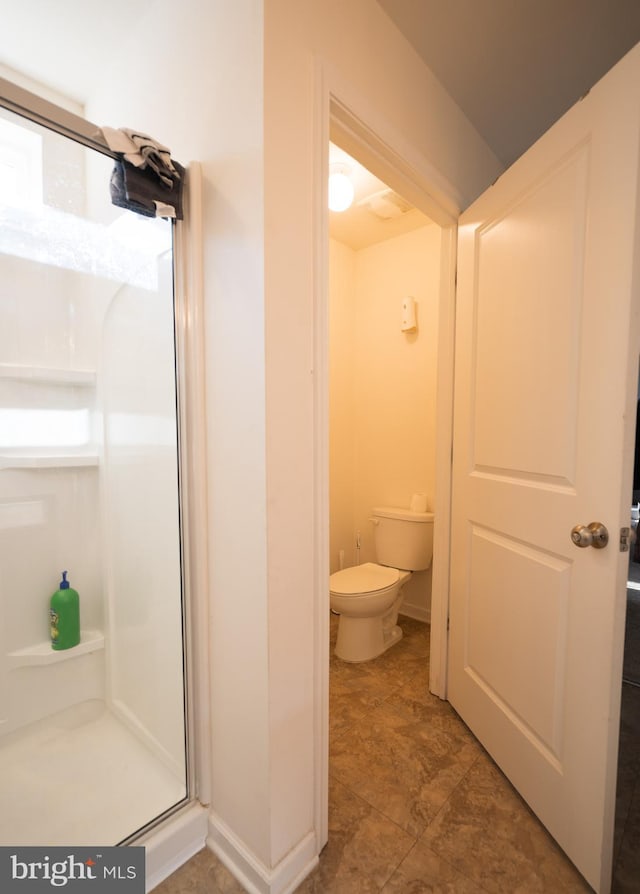 bathroom with toilet and a shower with shower door