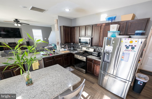 kitchen featuring dark brown cabinetry, sink, tasteful backsplash, hardwood / wood-style flooring, and stainless steel appliances