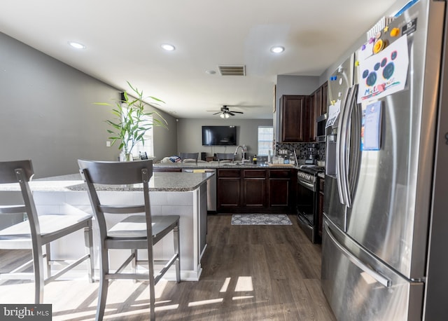 kitchen featuring sink, dark wood-type flooring, a breakfast bar, stainless steel appliances, and kitchen peninsula