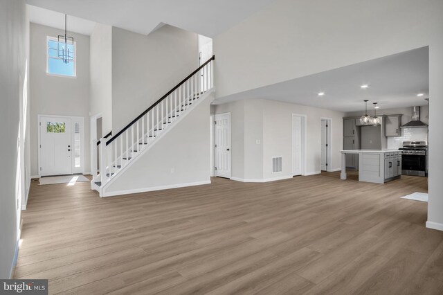111 Jennifer Cir, Harrisburg, PA 17112 - unfurnished living room with a chandelier, a high ceiling, baseboards, stairs, and light wood-style floors