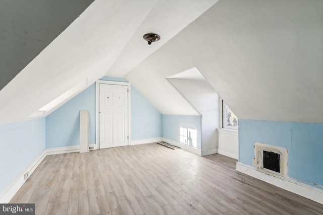 bonus room with vaulted ceiling, light hardwood / wood-style floors, and heating unit