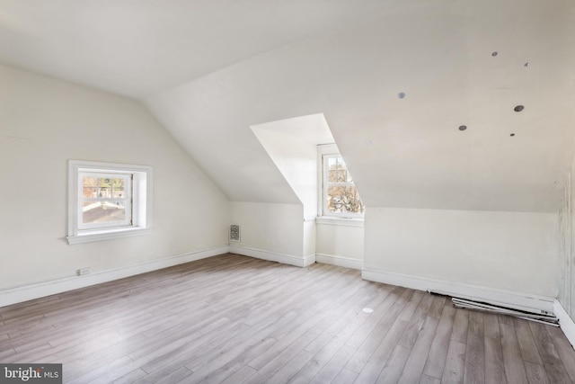 additional living space featuring vaulted ceiling and light wood-type flooring