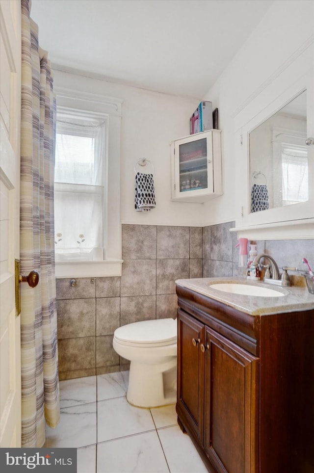 bathroom with vanity, a wealth of natural light, tile walls, and toilet