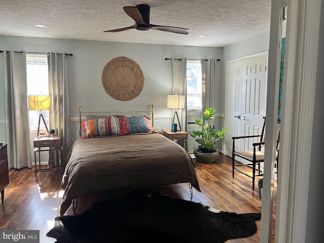 bedroom featuring a textured ceiling, multiple windows, and hardwood / wood-style floors