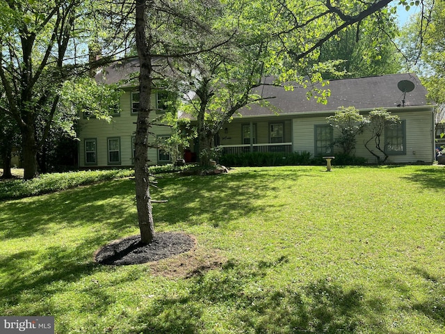view of front of home featuring covered porch, a chimney, and a front yard