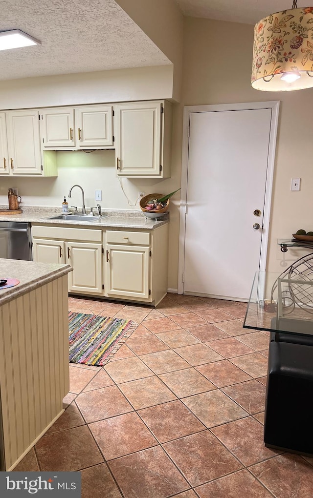 kitchen with white cabinets, a sink, light countertops, a textured ceiling, and stainless steel dishwasher