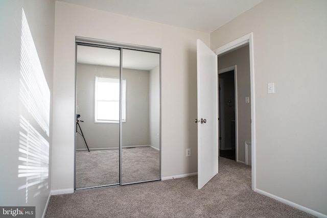 unfurnished bedroom with light colored carpet and a closet