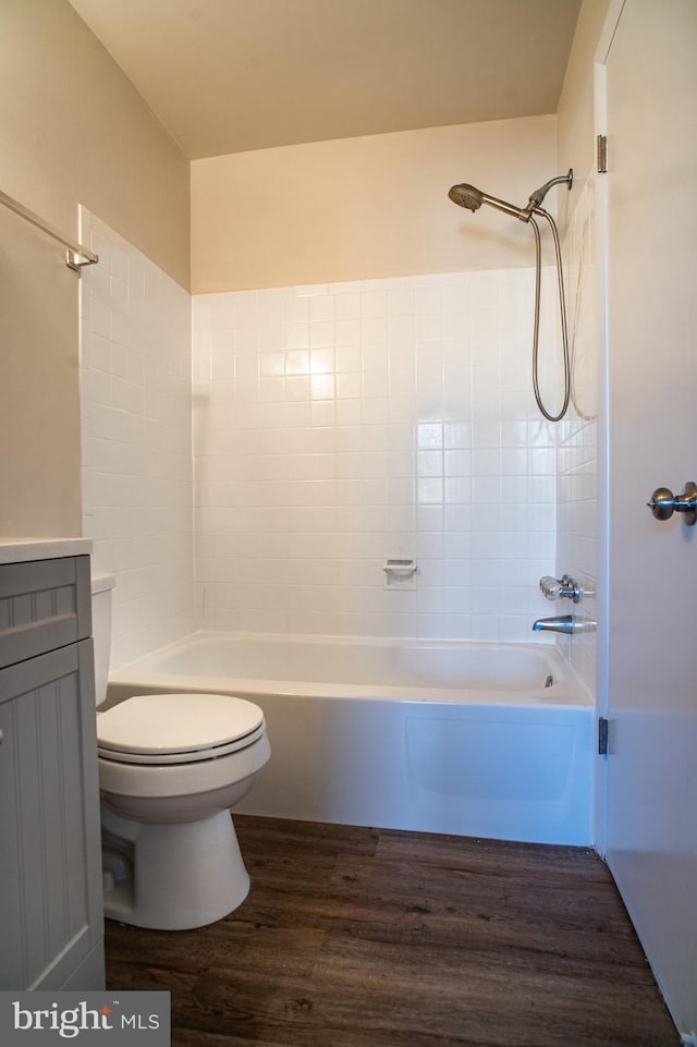 full bathroom with tiled shower / bath combo, vanity, hardwood / wood-style floors, and toilet