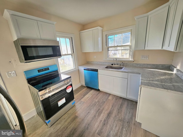 kitchen with stainless steel appliances, white cabinetry, sink, and light hardwood / wood-style flooring