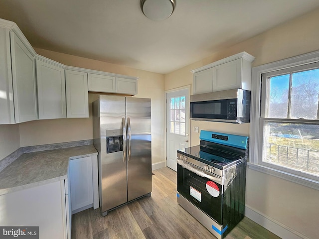 kitchen featuring appliances with stainless steel finishes, white cabinets, and light hardwood / wood-style flooring