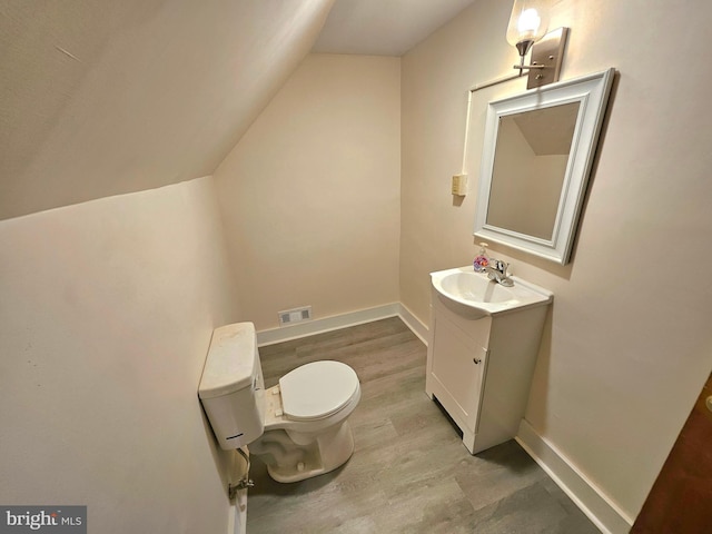 bathroom with vanity, wood-type flooring, vaulted ceiling, and toilet