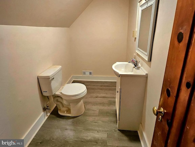 bathroom with hardwood / wood-style flooring, lofted ceiling, toilet, and vanity