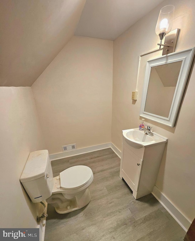 bathroom with vanity, hardwood / wood-style flooring, lofted ceiling, and toilet