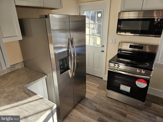 kitchen with dark wood-type flooring, stainless steel appliances, and white cabinets