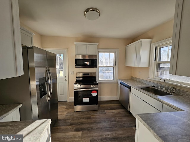 kitchen with appliances with stainless steel finishes, sink, white cabinets, and dark hardwood / wood-style flooring