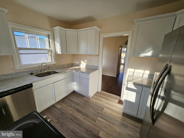 kitchen with white cabinetry, sink, wood-type flooring, and appliances with stainless steel finishes