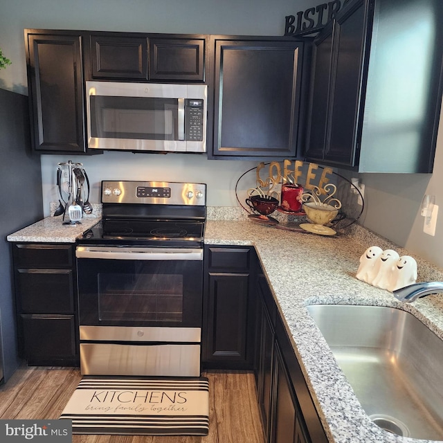 kitchen featuring stainless steel appliances, light stone countertops, sink, and light hardwood / wood-style floors