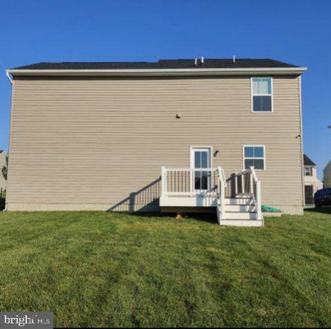 back of house featuring a deck and a lawn