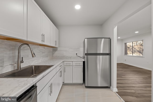 kitchen with sink, light stone counters, white cabinets, stainless steel appliances, and backsplash