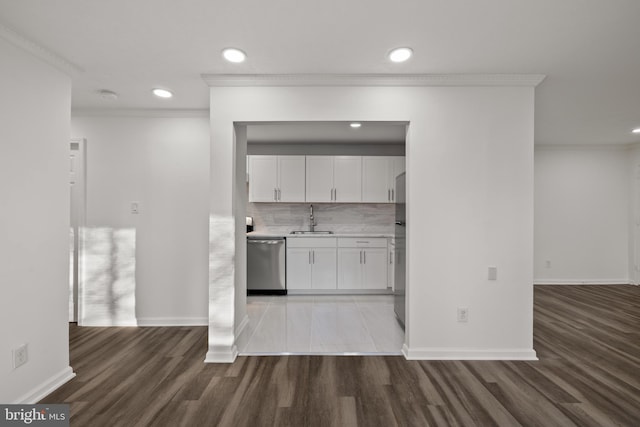 kitchen featuring white cabinetry, sink, decorative backsplash, ornamental molding, and stainless steel appliances