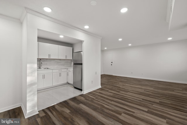 kitchen featuring sink, hardwood / wood-style flooring, stainless steel fridge, white cabinets, and decorative backsplash