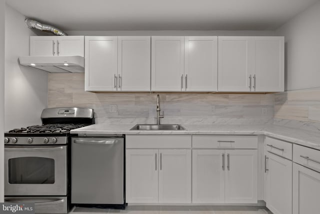 kitchen with sink, white cabinets, backsplash, stainless steel appliances, and light stone countertops