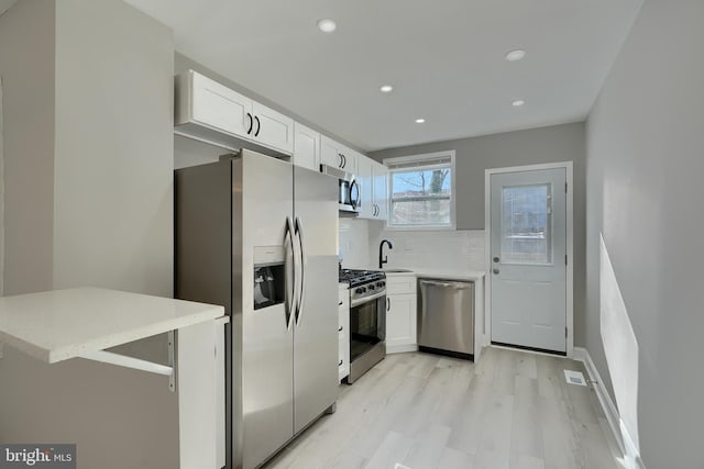 kitchen with white cabinetry, stainless steel appliances, sink, and backsplash