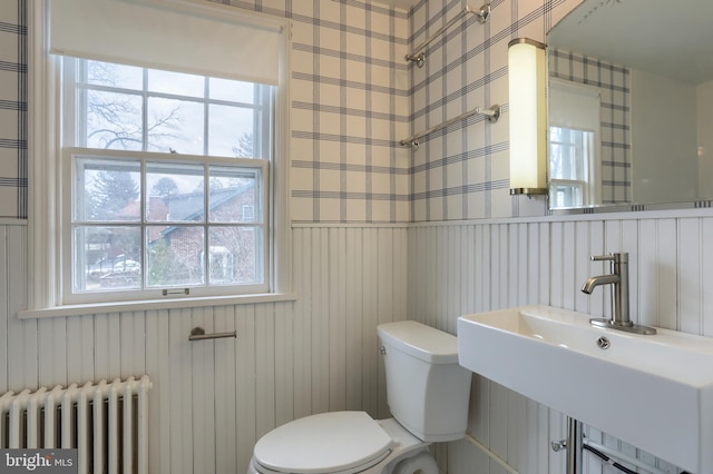 bathroom with radiator heating unit, toilet, and sink