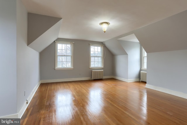 additional living space featuring vaulted ceiling, radiator, and light wood-type flooring