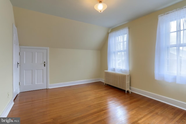 additional living space with light hardwood / wood-style flooring, radiator heating unit, and plenty of natural light