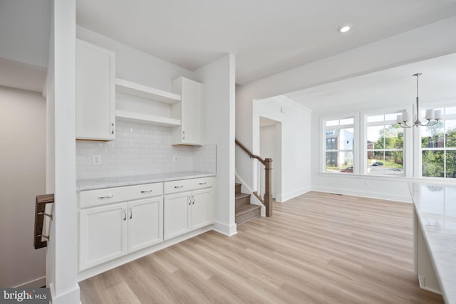 kitchen featuring a notable chandelier, pendant lighting, light hardwood / wood-style floors, decorative backsplash, and white cabinets