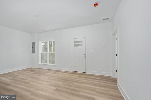 spare room with electric panel and light hardwood / wood-style floors