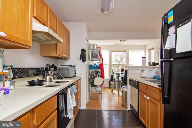 kitchen with electric range oven, dark hardwood / wood-style floors, dishwasher, and black fridge